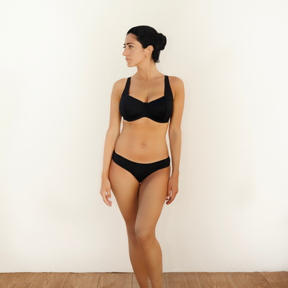 Black Balconette Shaped Swimwear snug bikini  top and classic bikini briefs worn by greek model looking at the side on a white backgrond